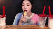 a woman is eating a piece of cake in front of two cups of milk tea