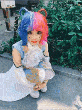 a girl with pink and blue hair is kneeling down