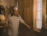 a man wearing a chef 's hat is opening a door in a room .