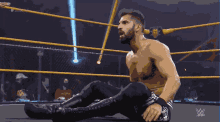 a wrestler is laying on the ground in a wrestling ring with the letters w on the bottom right