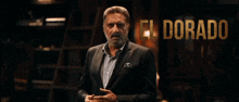 a man in a suit stands in front of a sign that reads el dorado