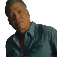 a man in a denim shirt is looking at the camera