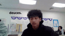 a man in a classroom with the word deuces on the wall behind him