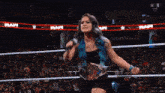 a woman with blue hair is standing in front of a crowd at a wrestling match .