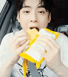 a man in a car is eating a bag of chips