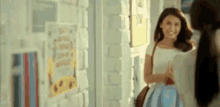two women are standing in a hallway talking to each other and smiling .