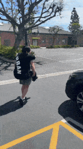 a man wearing a black urban shirt is carrying a large bag
