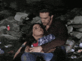 a man holds a woman in his arms while they sit in the grass