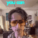 a man wearing sunglasses and a plaid shirt with the words you can behind him