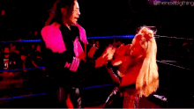 a man in a pink jacket is standing next to a blonde woman in a red dress .
