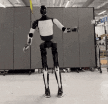 a black and white robot is standing in front of a wall with a yellow sticker on it