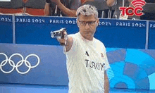 a man is holding a gun in front of a sign that says 2024 .