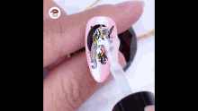 a person is painting a unicorn on their nails with a brush .