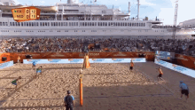 a beach volleyball game is being played in front of a large ship that says ' amsterdam ' on it