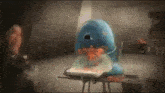 a blue whale is sitting in a high chair eating carrots .