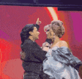 two women are dancing on a stage and one of them is pointing at the other .