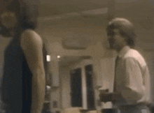 a man and a woman are standing next to each other in a living room .