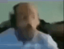 a man with a beard is sitting on a couch with his eyes closed .