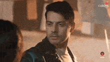 a man in a leather jacket is looking at another man in a white shirt ..