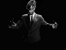 a black and white photo of a man in a suit with dreadlocks