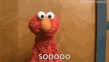 elmo from sesame street is standing in front of a wall and saying s00000 .