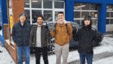 a group of men standing in front of a garage giving the thumbs up