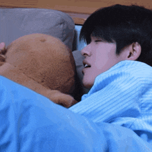a man in a blue striped shirt is sleeping with a stuffed animal