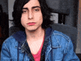 a young man wearing a denim jacket and a pink shirt