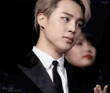a close up of a man in a suit with a woman in the background