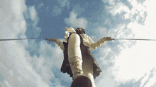 a person is standing on a rope with a sword in their hand .