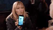 a woman is holding a cell phone with a picture of a man on the screen