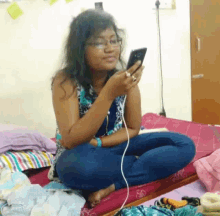 a woman is sitting on a bed looking at her cell phone