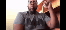 a man wearing a batman t-shirt and glasses is blowing a kiss .
