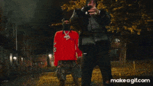 a man wearing a ski mask is holding a necklace and a ring .