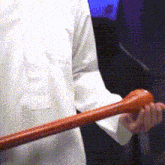 a man in a white shirt holds a wooden bat