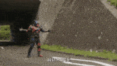 a man in a superhero costume is standing on a road and says best match