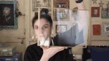 a woman is holding up a picture frame with a picture of a man in it