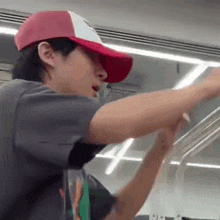 a man wearing a red and white hat and a gray shirt is standing in a train .