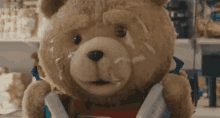 a teddy bear with a dirty face is holding a book in his hands .