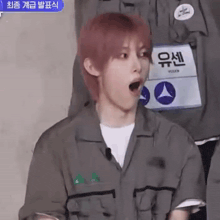 a young man with pink hair is wearing a gray shirt and a white shirt .