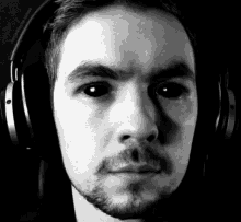 a man wearing headphones has black eyes and a beard .