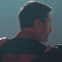 a close up of a man 's face with a black and red jacket on