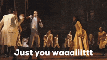 a group of people are dancing on a stage and the words just you waaaiiittt are on the bottom of the image