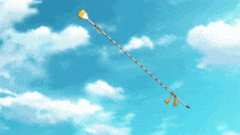 a very long stick is flying through a blue cloudy sky