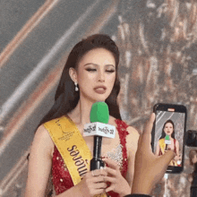 a woman wearing a sash that says sao ui is holding a microphone