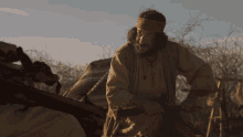 a man with a beard wearing a headband holds a wooden stick
