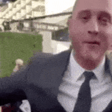 a man in a suit and tie is making a funny face while standing on a red carpet .