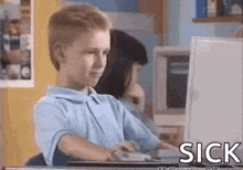 a young boy is sitting at a desk in front of a computer monitor .