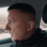 a man in a black jacket is sitting in a car