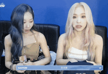 two women are sitting next to each other with a sign that says gahyun on it